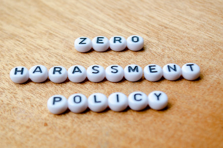 Zero Harassment Policy Text on white button on wooden table.の写真素材