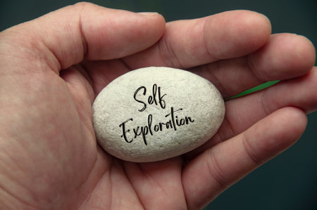 Hand holding Zen stone with Self Exploration text engraved on the stone.