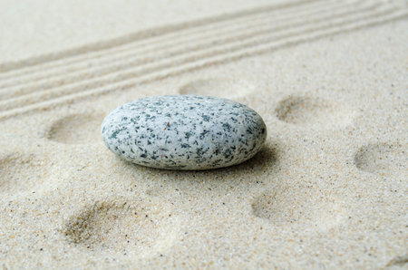 Empty zen stone on beach sand with customizable space for text or message ideas.