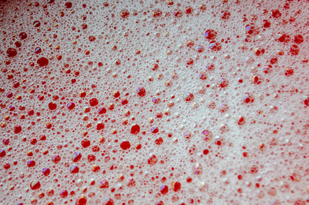 Macro view of bubbles forming on the water surface with red background.の写真素材