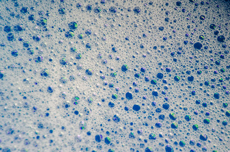 Macro view of bubbles forming on the water surface with blue background.