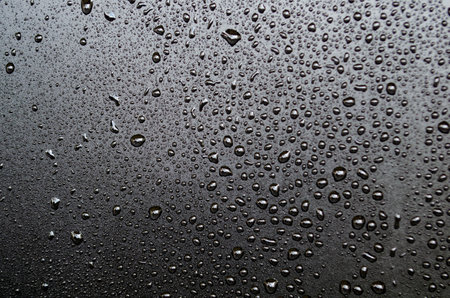 Water drops on black background. Raindrops on black glass. Close up.の写真素材