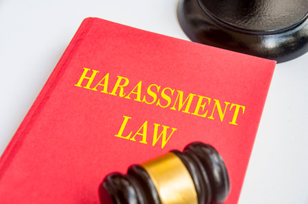 Side view of Harassment Law book with gavel on white background. Zero harassment concept.の写真素材