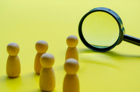 Wooden figure dolls standing looking at magnifying glass.の写真素材