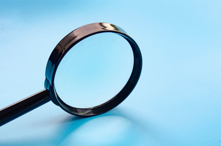 Side view of magnifying glass on blue cover background with customizable space for text or ideas.の写真素材