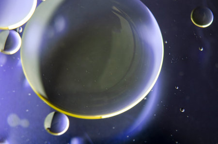 Close-up of iridescent oil streaks on water, with a smooth dark gradient background.
