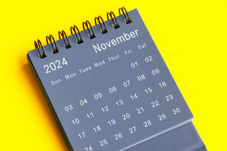 Top view of November 2024 black desk calendar on yellow cover background.の写真素材