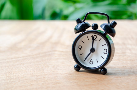 Table alarm clock pointing at 7pm or 7am with customizable space for text. Time management concept and copy spaceの写真素材