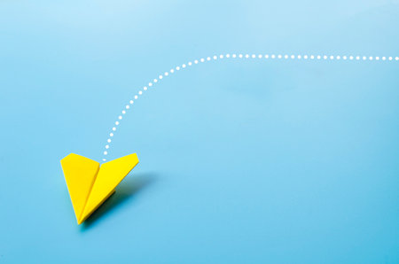 Low view of origami yellow paper airplane on blue background.の写真素材