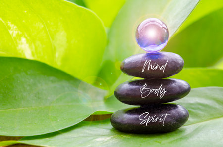 Mind, Body and Spirit text on black zen stones with blue shining glass marble on top. Zen concept.の写真素材