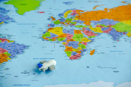 Top view of small toy airplane placed on a world map representing travel or global exploration. Travel and destination concept.の写真素材