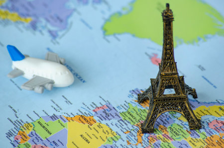 Small toy airplane and a miniature Eiffel Tower placed on a world map. Travel destination concept.