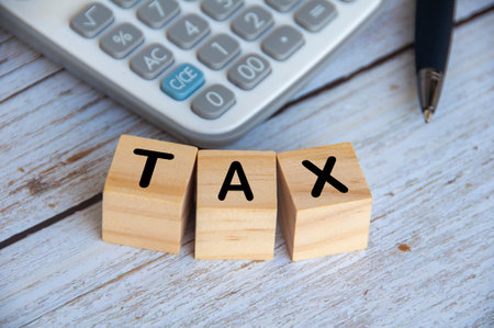 Top view of Tax Time text on wooden cubes with calculator background.