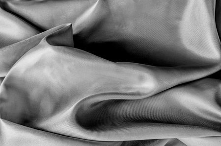 Close up of luxurious black silk fabric with elegant folds and smooth, glossy surface textureの写真素材