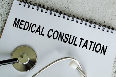 Top view of Medical Consultation Text on white paper notepad with stethoscope on wooden table background. Health and medical conceptの写真素材