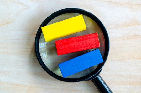 Top view of multicolored wooden blocks with magnifying glass with customizable space on wooden block...
