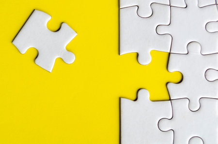 Connecting missing white jigsaw puzzle symbolizes partnership and unity on yellow background.の写真素材