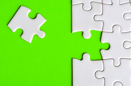 Connecting missing white jigsaw puzzle symbolizes partnership and unity on green background.の写真素材