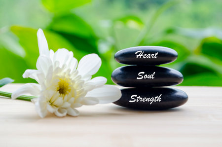 Heart, Soul and Strength text on zen stones with white color flower and blur background