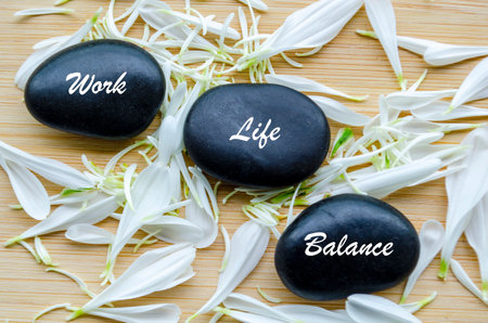 Top view of Work Life Balance text on zen stones with white color flower petalsの写真素材