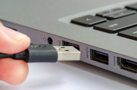 USB being plugged into laptop highlighting risk of unauthorized data transfer or malware.