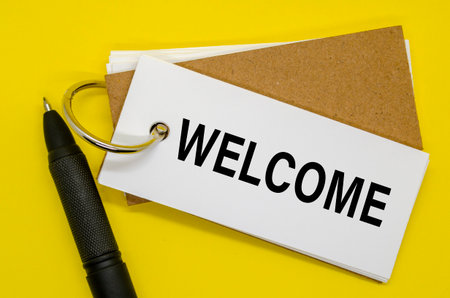 Open notebook with WELCOME sign on the front, upright pen beside it.の写真素材