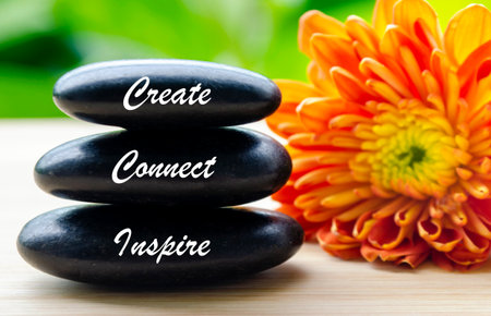 Stack of zen stones with the word create next to vibrant flower.