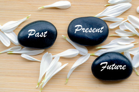 Zen stones labeled past, present, future on calming background for mindfulness.