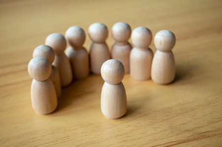 A Figure Facing Beige Pegs In Formation On Wood Surface.の写真素材