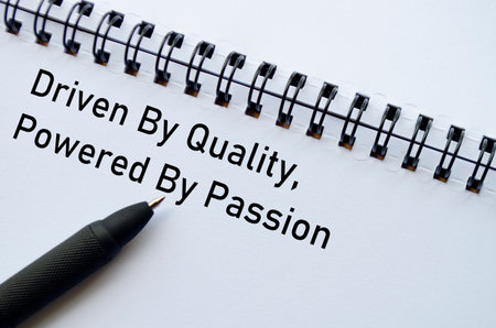 Driven By Quality Powered By Passion on notebook with pen on wooden surface.の写真素材