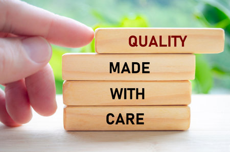 Quality made with care text on wooden blocks being gently pushed by hand represents thoughtful, intentional craftsmanshipの写真素材