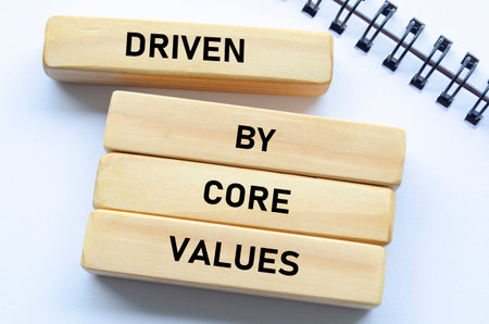 Driven by core values text on wooden blocks and notebook represents purposeful direction guided by foundational beliefsの写真素材