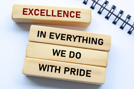 Excellence in everything we do with pride text on wooden blocks and notebook reflects unwavering quality and pride in every actionの写真素材