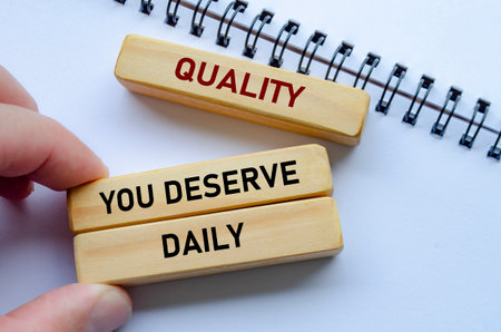 Quality you deserve daily text on wooden blocks and notepad reinforces consistency as a daily habit of excellenceの写真素材