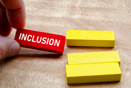 Hand putting Inclusion word on red blocks into the yellow blocks. Diversity and inclusion concept.の写真素材