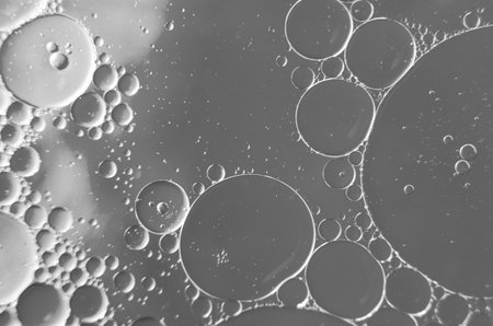 Close up of oil on water, reflecting a subtle black and white background