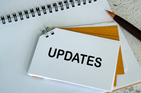 Top view of Updates text on white notepad. Business update concept