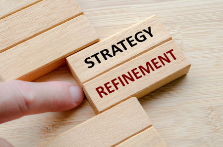 STRATEGY REFINEMENT text on wooden blocks, Strategic adjustments to refine core business direction and improve competitive market positioning.の写真素材