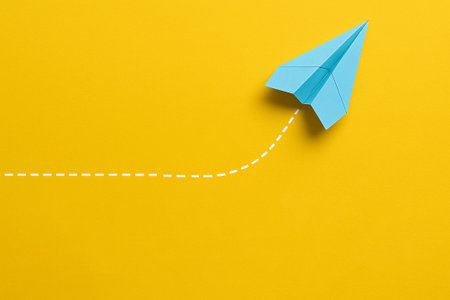 A yellow airplane moving ahead with dotted path symbolizing leadership initiative.の素材