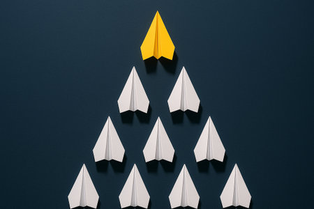 A yellow airplane at the top of a black triangle of airplanes symbolizing leadership dominance and strength.の素材