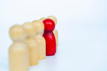 A red figure squeezed tightly between wooden figures, representing leadership or conflict or bullying concept.の写真素材