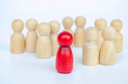A red figure leading the rest of the wooden group, representing leadership or exclusion concept.の写真素材