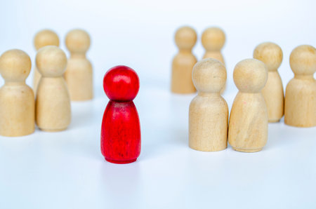 A red figure isolated from the other wooden group, representing leadership or exclusion or discrimination concept.の写真素材