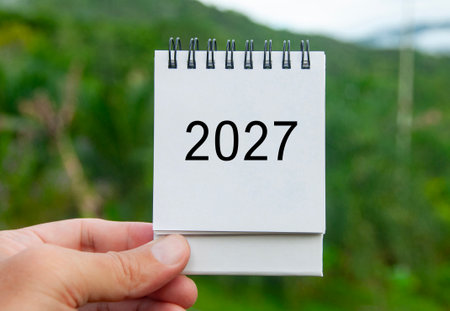 Hand holding 2027 white calendar with nature background. Holiday and calendar concept.の写真素材