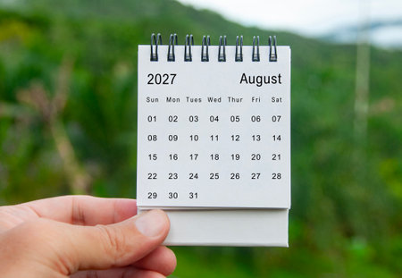Hand holding August 2027 white calendar with nature background. Holiday and calendar concept.の写真素材