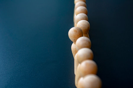Several plain beige wooden dolls aligned vertically on a white surface illustrating simplicity and uniformityの写真素材