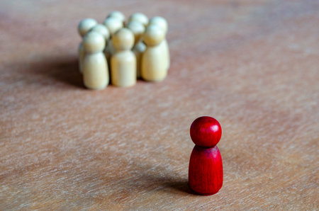 A red figurine apart from beige figurines symbolizing isolation that can indicate leadershipの写真素材