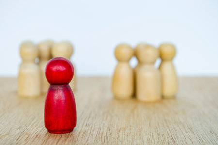 Red wooden figure among beige figures illustrating standout leadership conceptの写真素材
