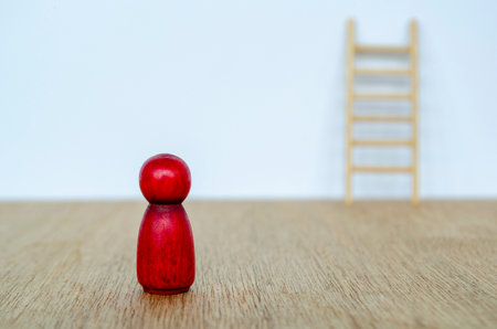 Red wooden figure leading group of beige figures depicting direction and motivation with customizable space for textの写真素材