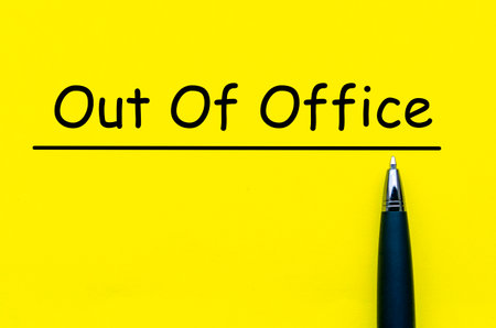Out Of Office, Yellow square paper with black pen below the underlined phrase symbolizing absence notification noteの写真素材